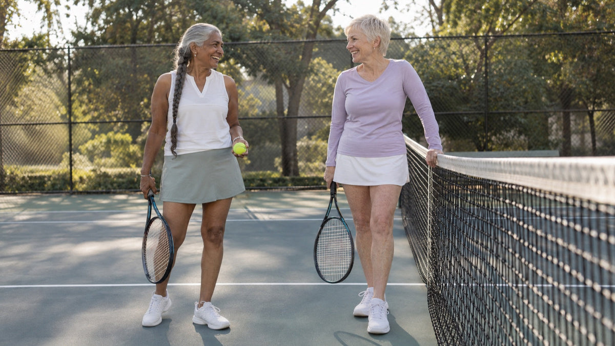Two older women pause between rallies on a neighborhood tennis court