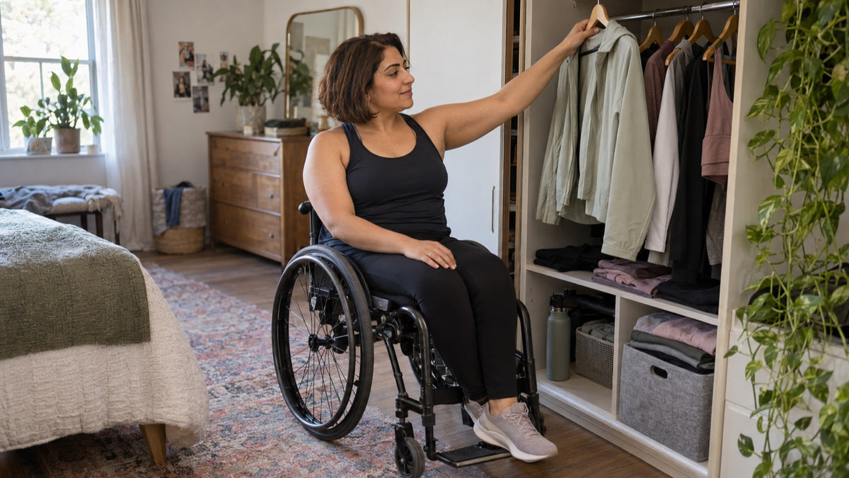 Wheelchair user selects a versatile activewear layer from an open wardrobe