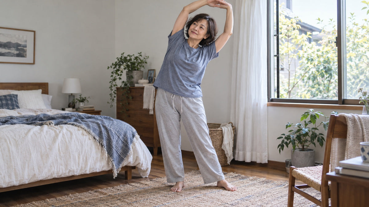 Older woman stretches comfortably in soft cotton loungewear at home