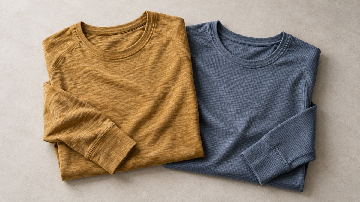 Two folded ochre and slate-blue long-sleeve base-layer tops with contrasting knit textures.